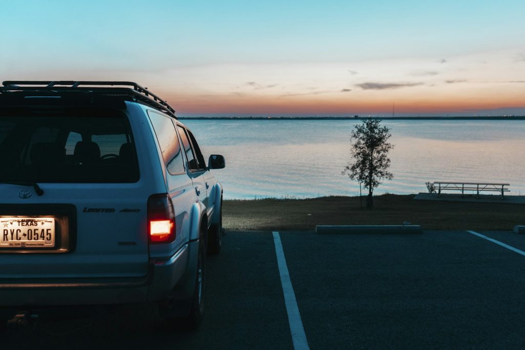 A car parked in a parking lot next to a body of water